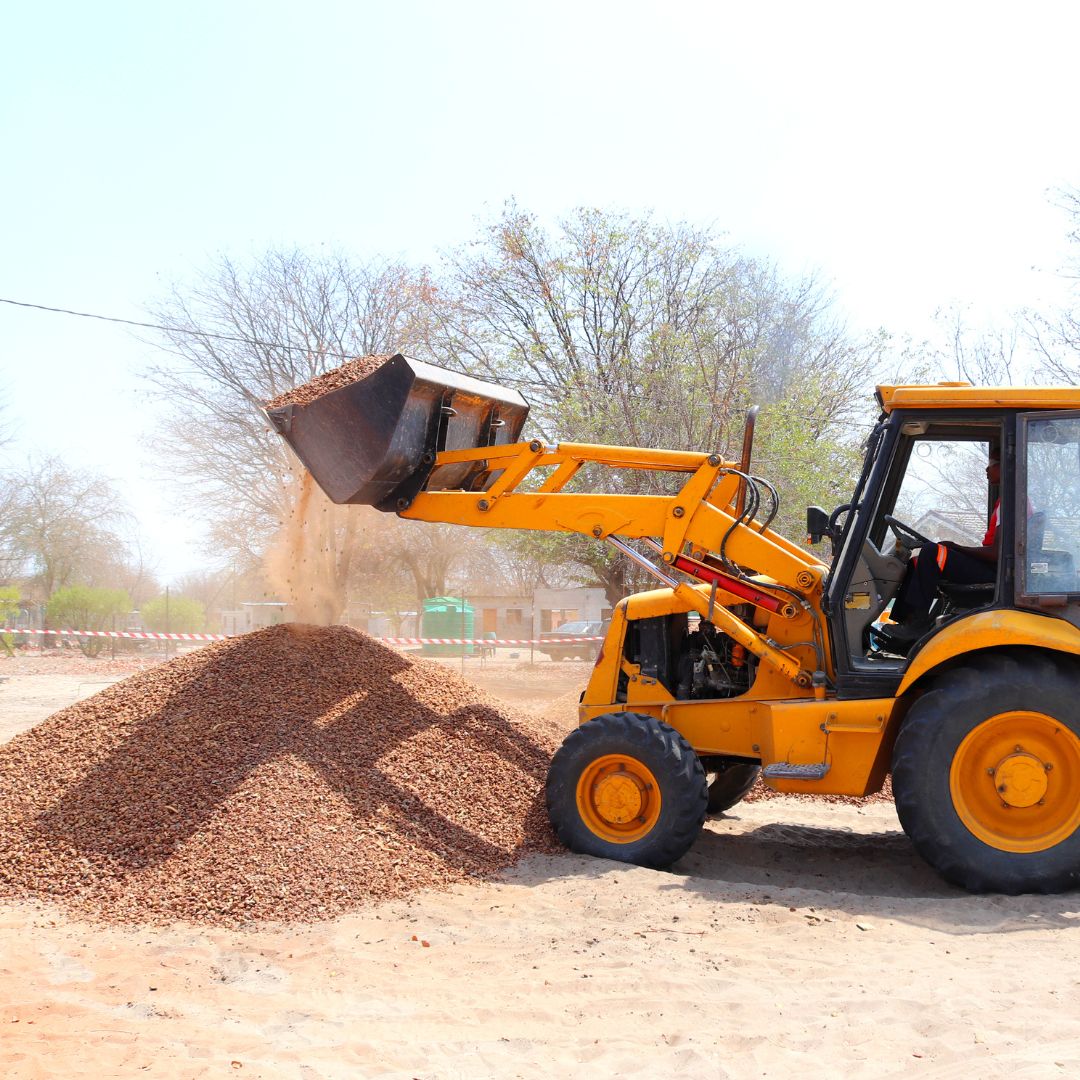 Mini pelle levant un stock de cailloux sur un chantier